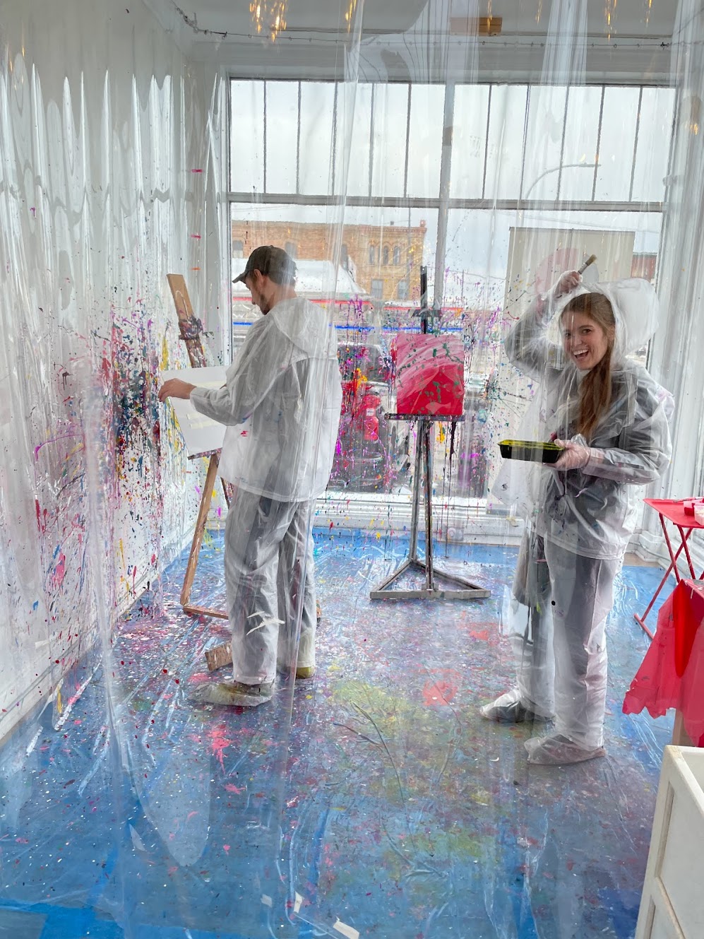 girl laughing and pulling her hood up while painting in the splatter paint studio at Foundry