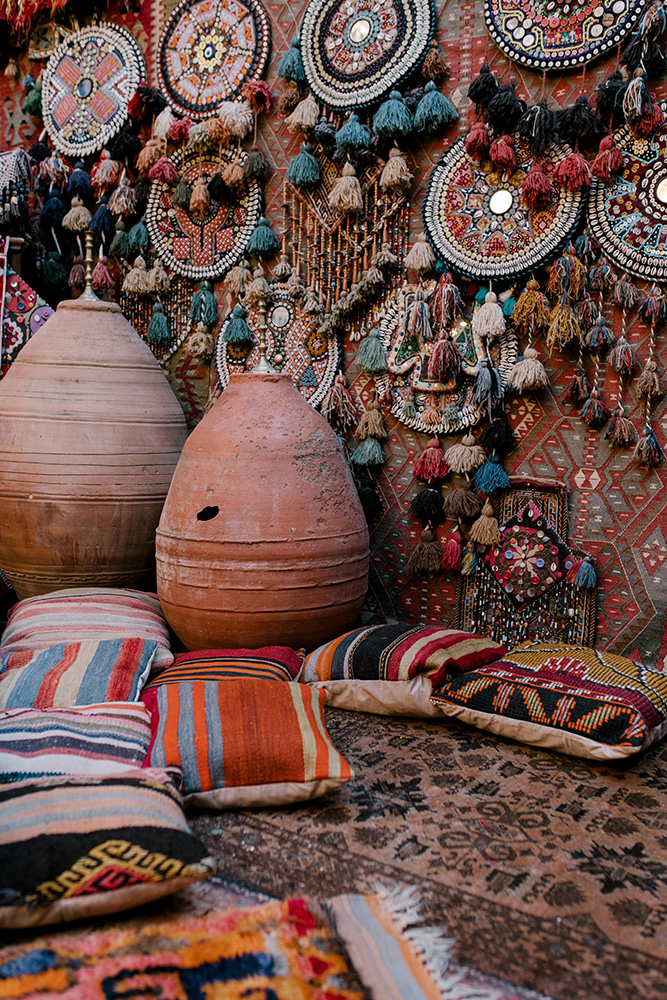 two large clay vessels in front of a terracotta wall of dream catchers 