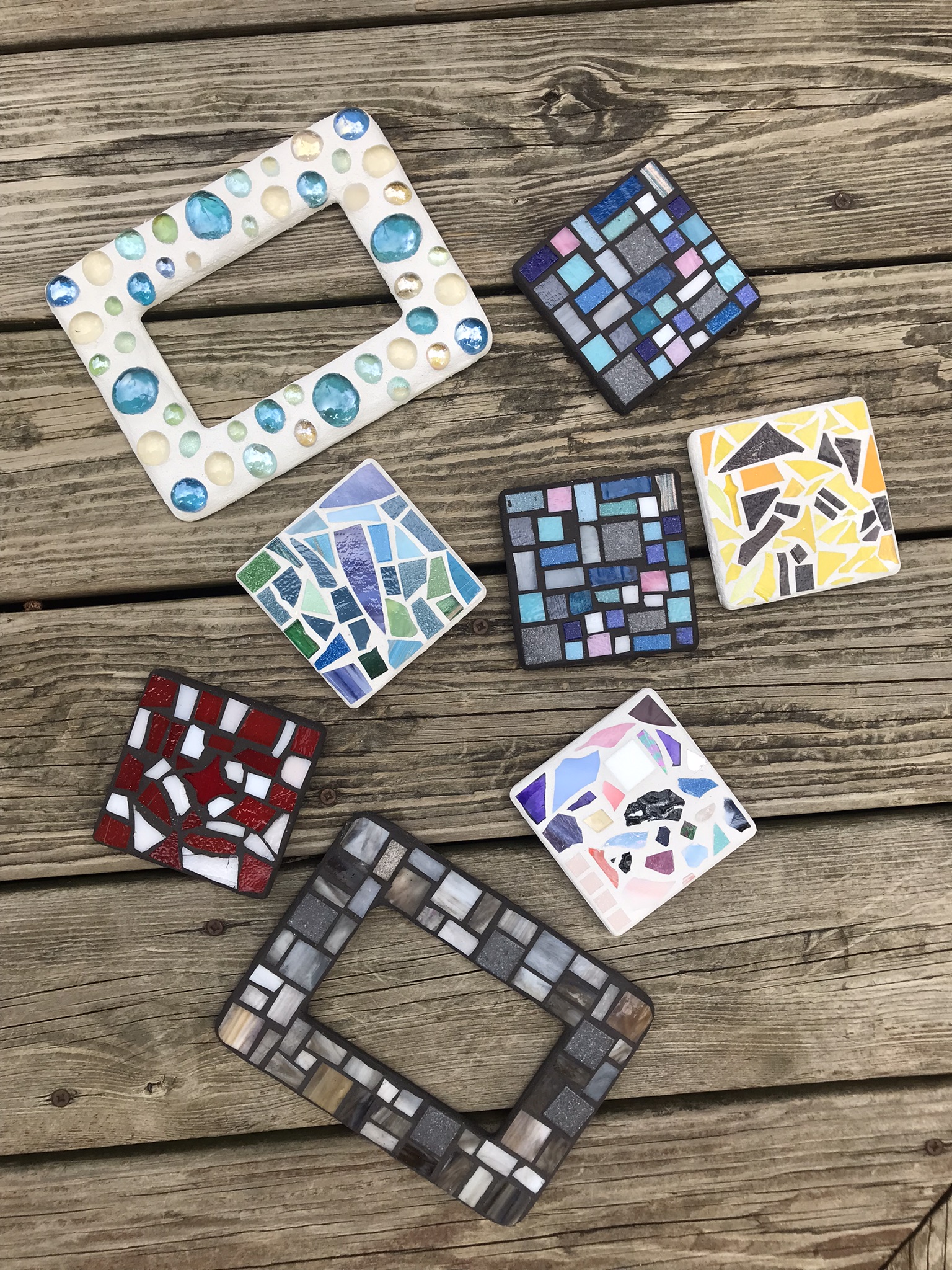 6 differently designed glass mosaic coasters and two mosaic picture frames made by students at Foundry in Port Huron