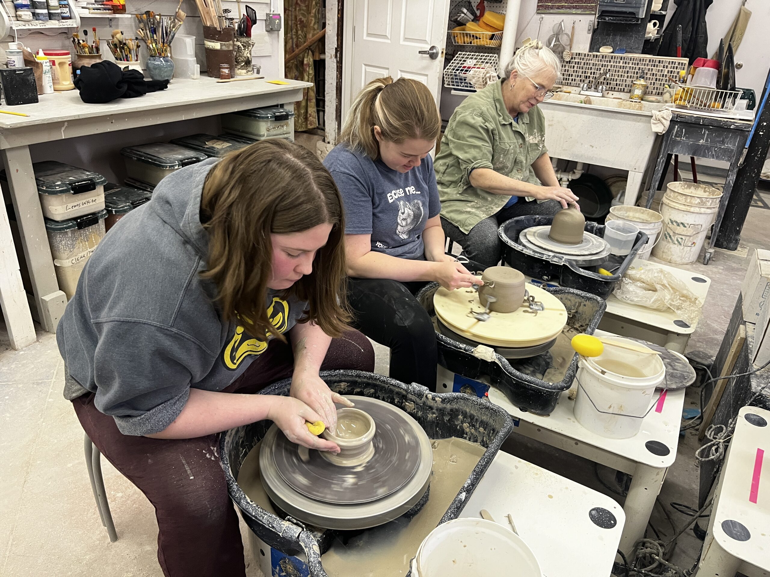 three students throwing pottery on wheels in Foundry's pottery studio