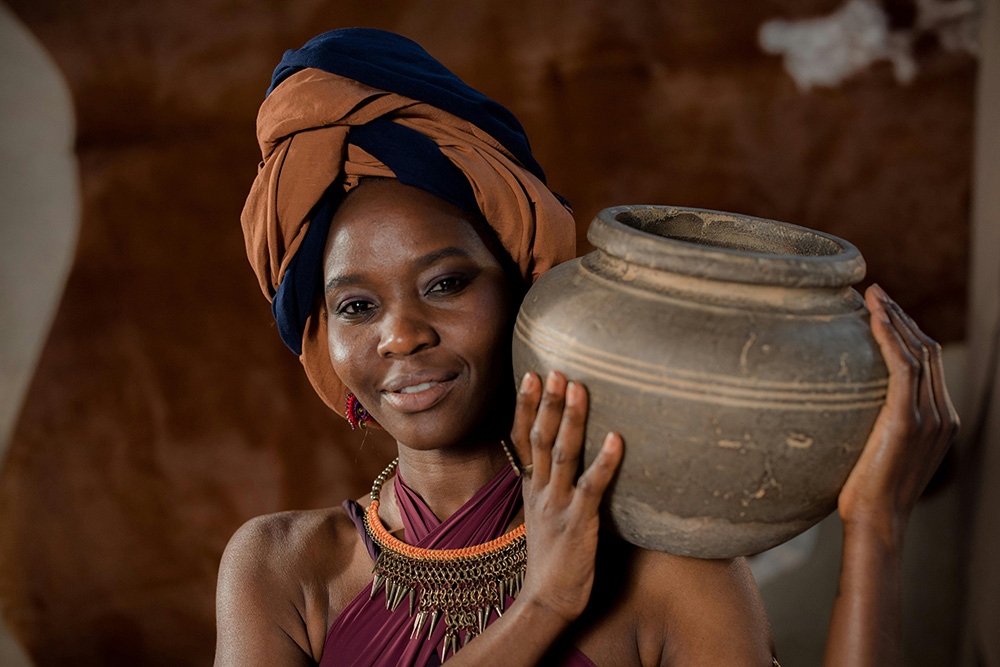 woman carrying a large clay pot on her shoulder