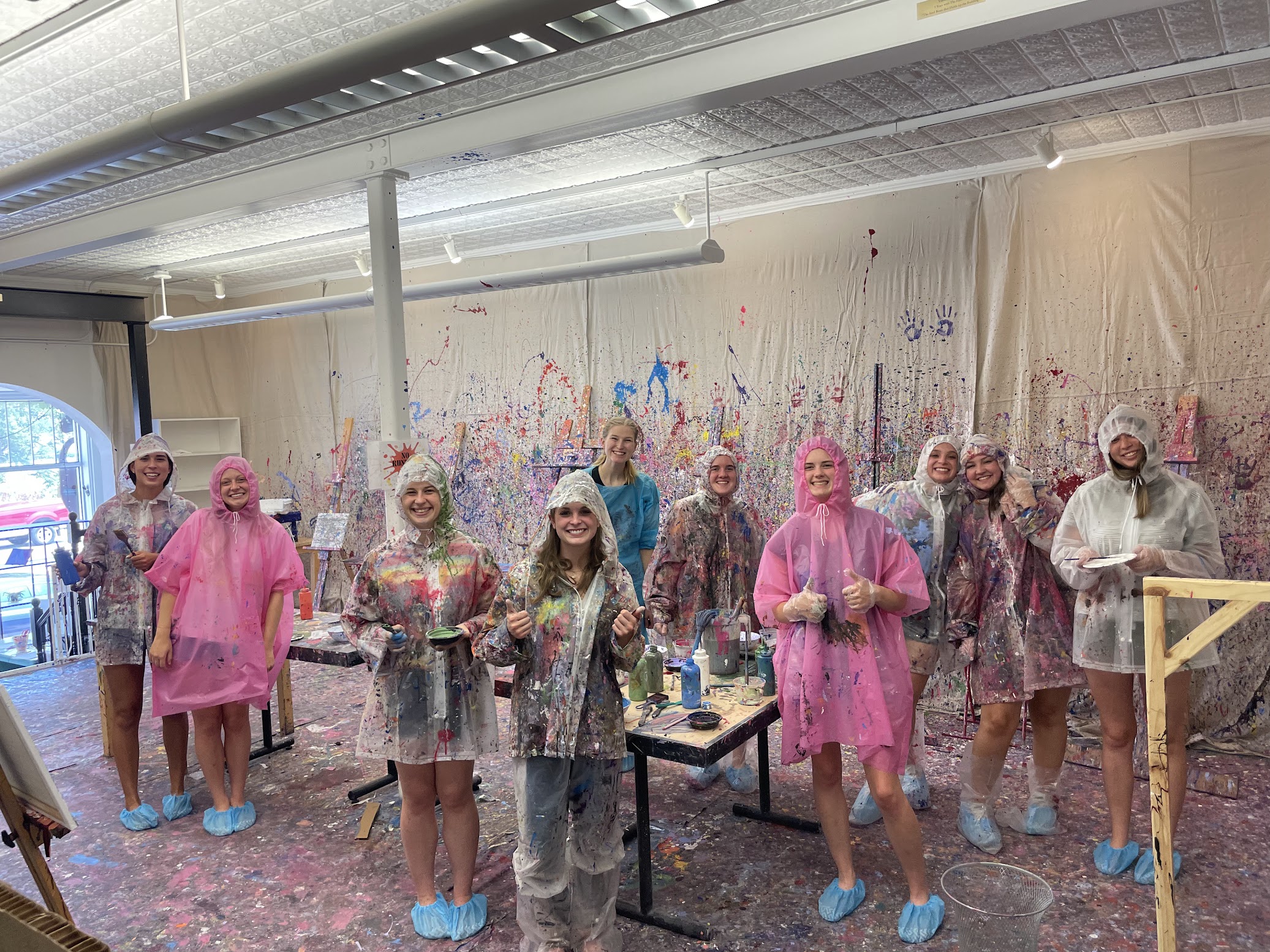 a group of 10 girls posing for a picture in Foundry's Splatter Paint studio during a bachelorette party