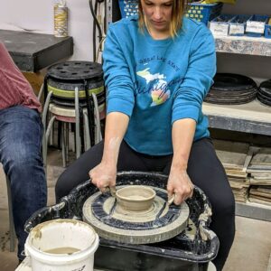 student removing clay from a pottery wheel in class at Foundry